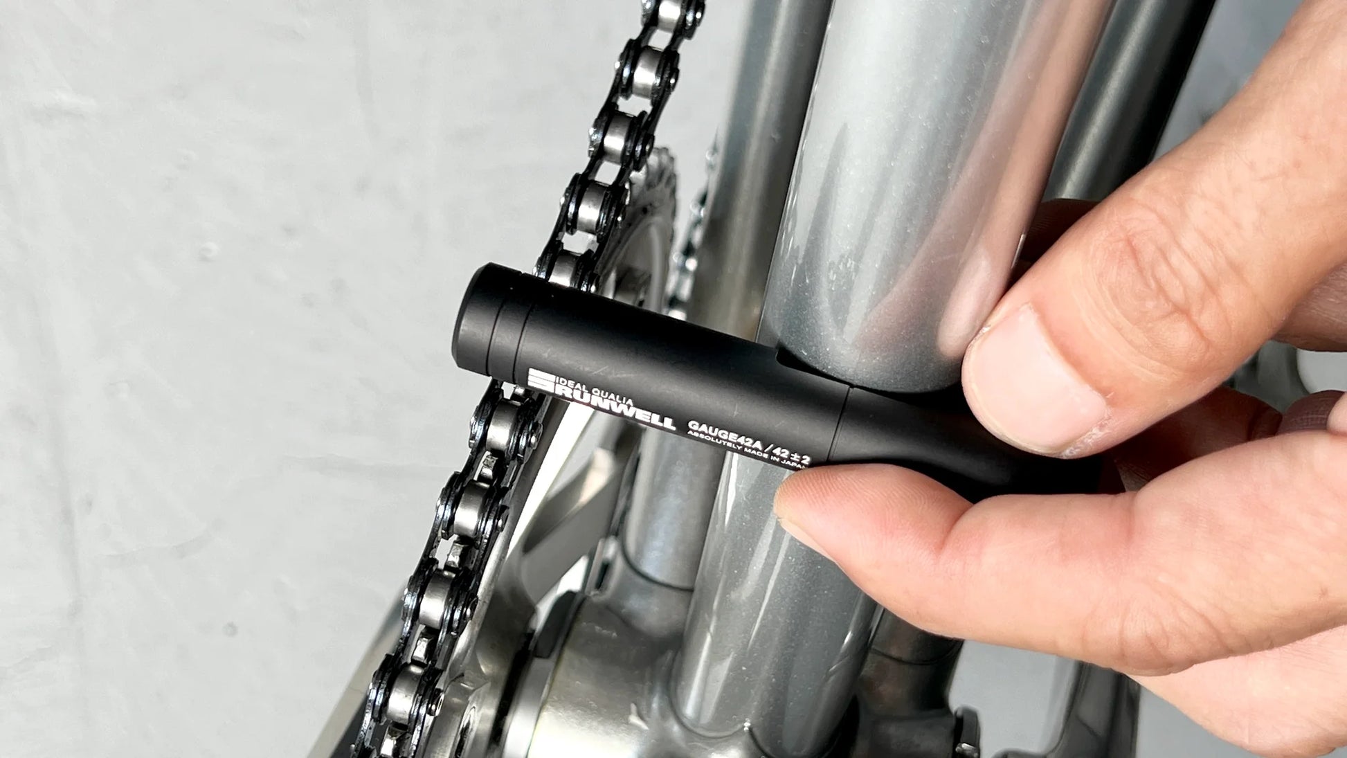 Product photo of a track chainline checker, in use on an NJS bicycle frame